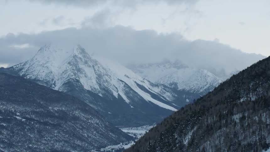 Clouds float above snowy mountains