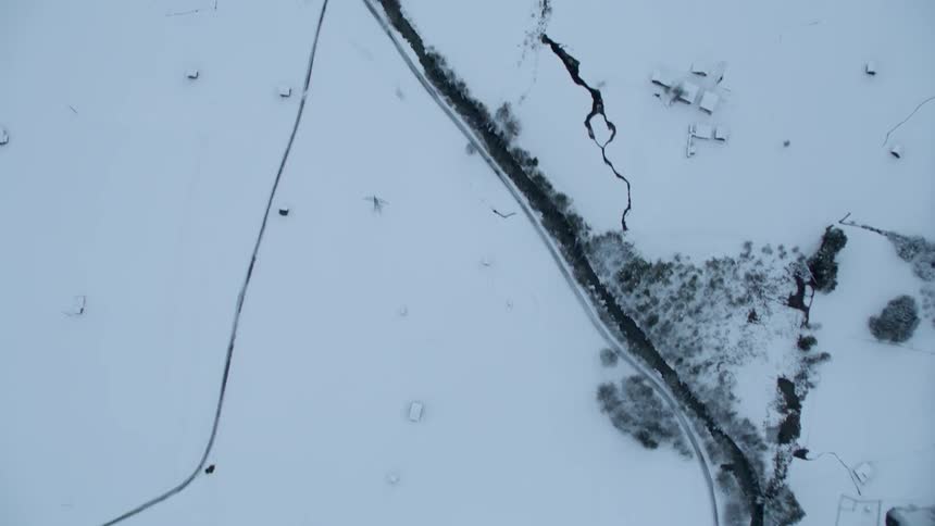 A stream runs through the snow covered field below