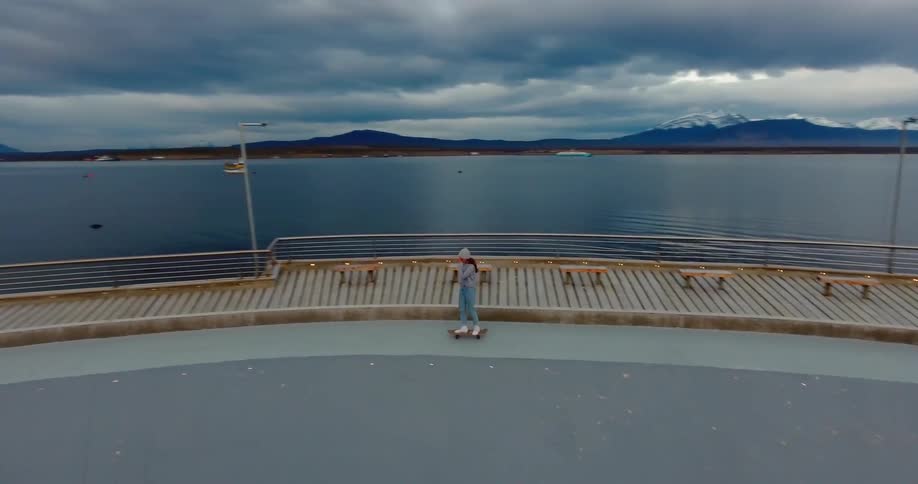 A skateboarder rides next to a mountain lake