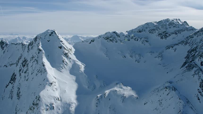 Clouds float above snowy mountains
