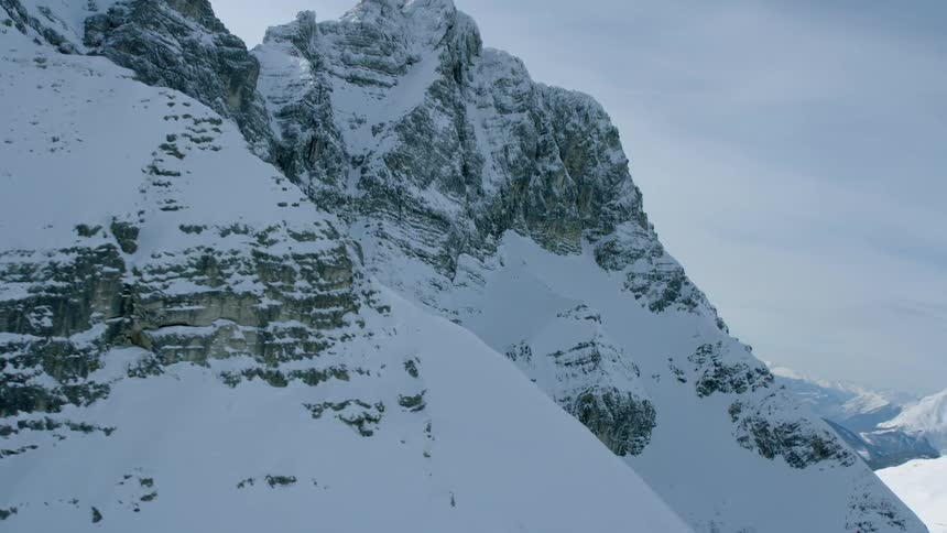 Snow is covering the slopes of a mountain range during the day