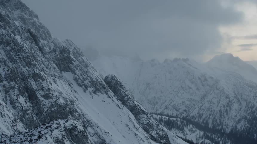 Clouds float over snowy mountains
