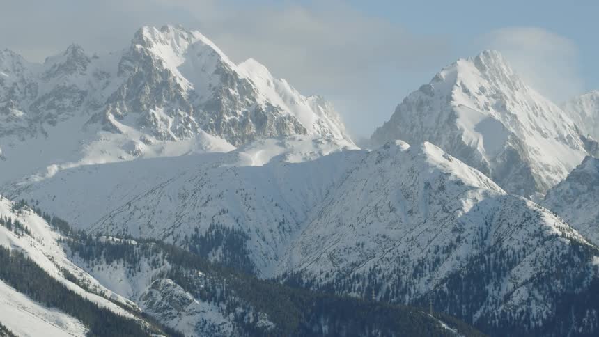 Clouds float above snowy mountains