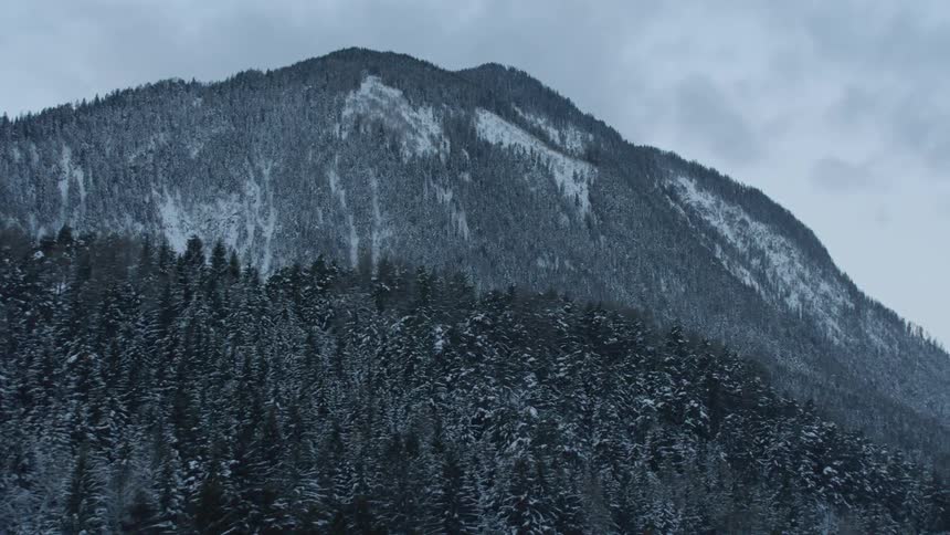 Clouds are hanging over a snow-covered mountain range during the day