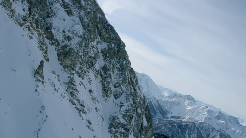 Snowy mountains sit under a cloudy sky