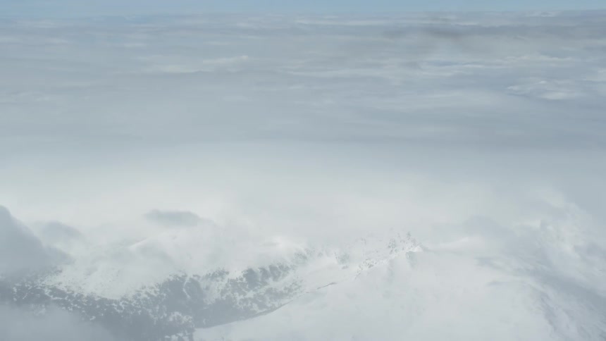 Clouds float above snowy mountains
