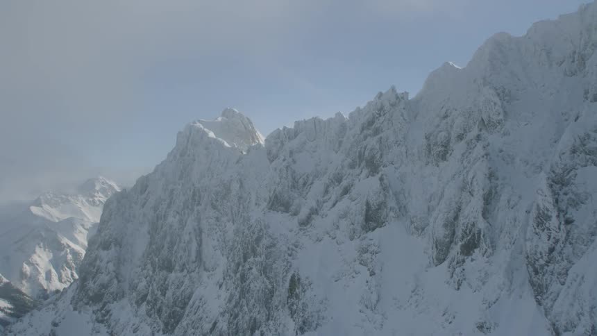 Clouds float above a snowy mountain ridge