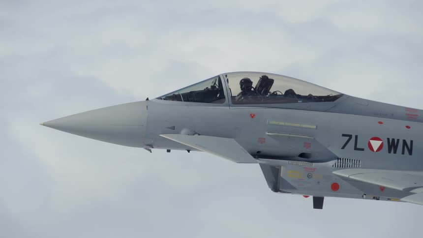 A pilot is flying a fighter jet above the clouds in daylight