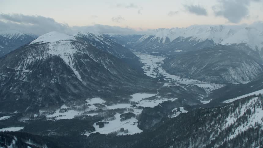 Clouds float above snowy mountains at sunset