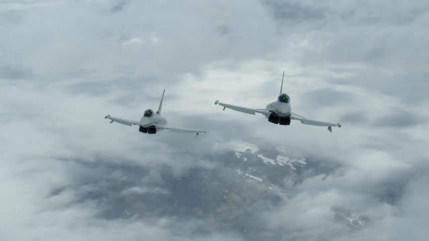 Two jets fly in formation above the clouds