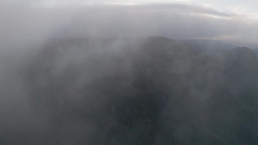 A plane flies through clouds in the sky
