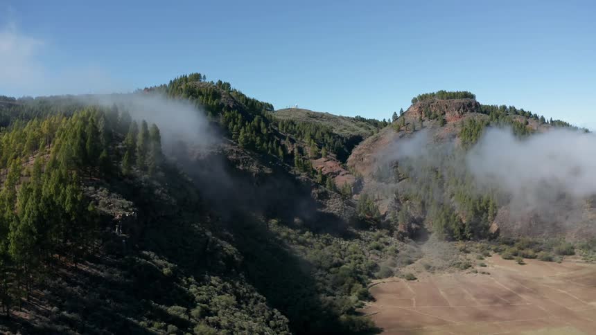 Clouds pass over trees and hills on a sunny day