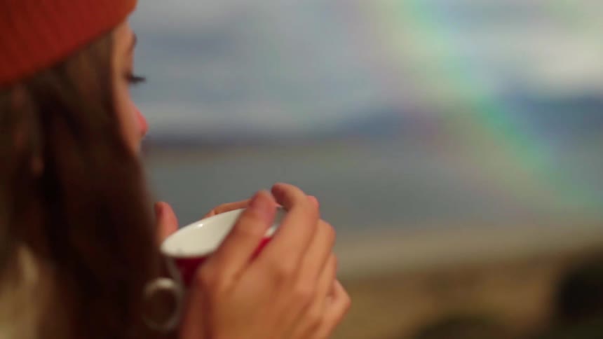 Woman takes a sip out of a mug on a sunny day