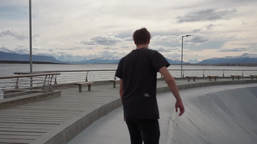 A skateboarder rides next to a lake