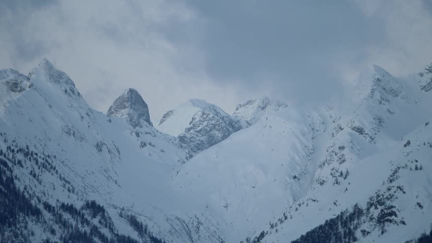 Clouds float above snowy mountain peaks
