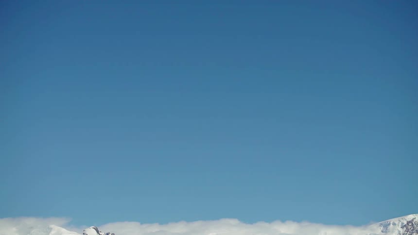 Clouds float above snowy mountains
