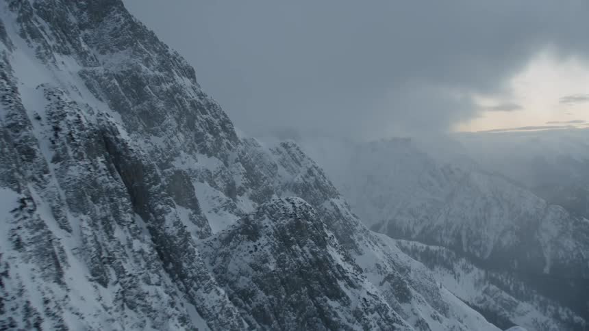 Clouds roll over snowy mountains