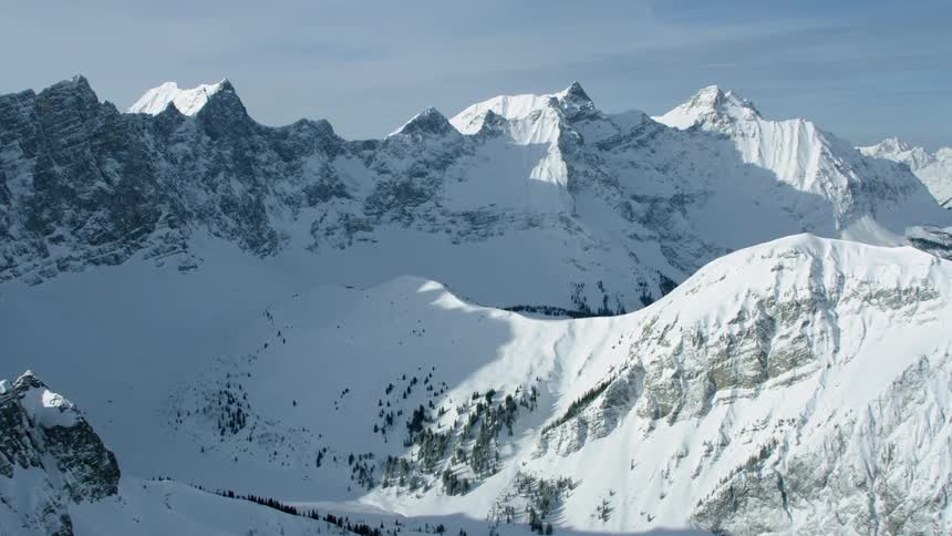 Snow is covering the slopes of a mountain range during the day