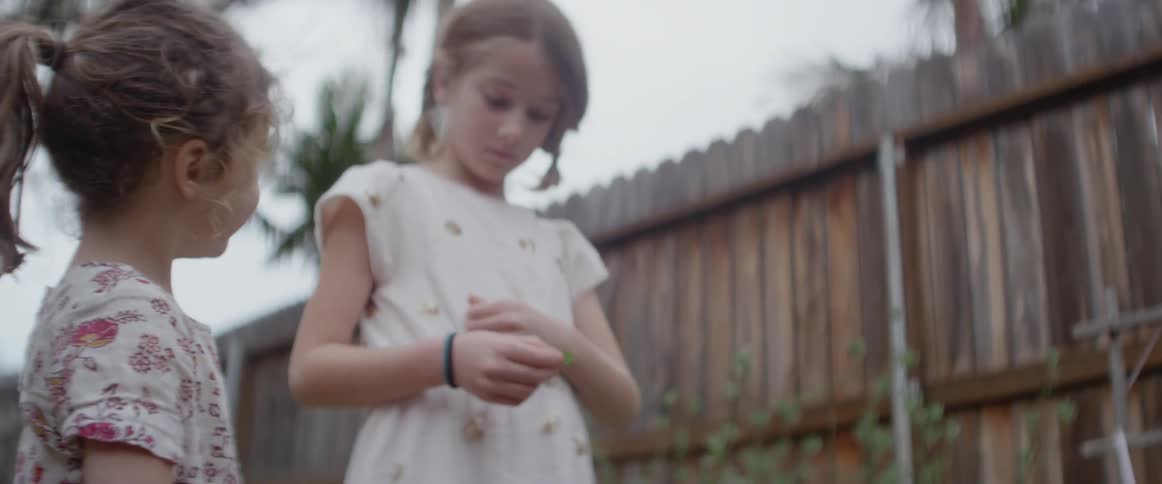 Two girls play in a backyard near a fence