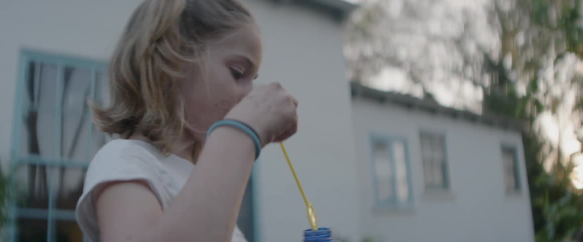 A girl blows bubbles outside at sunset