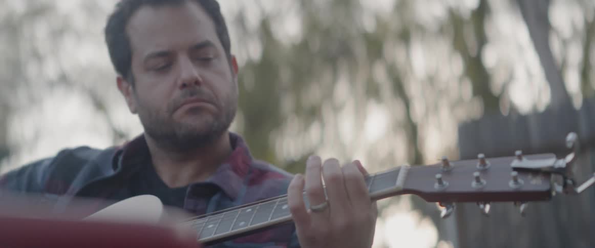 A man is playing the guitar outside