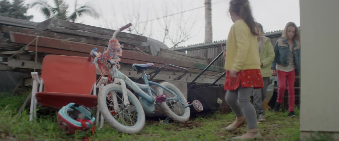 Three young kids play in a backyard