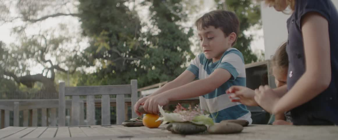 Kids squeeze an orange on a patio table