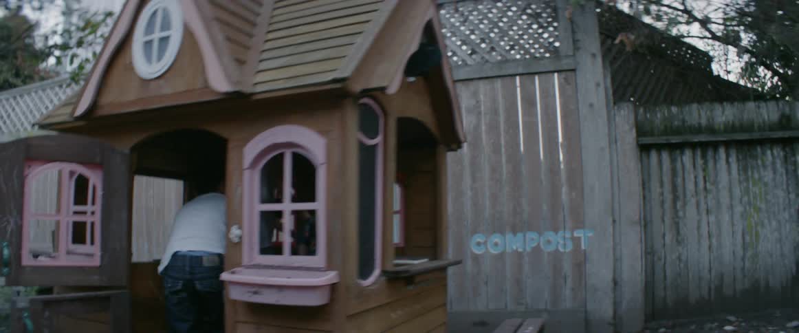 Children are playing in a playhouse in a backyard at dusk