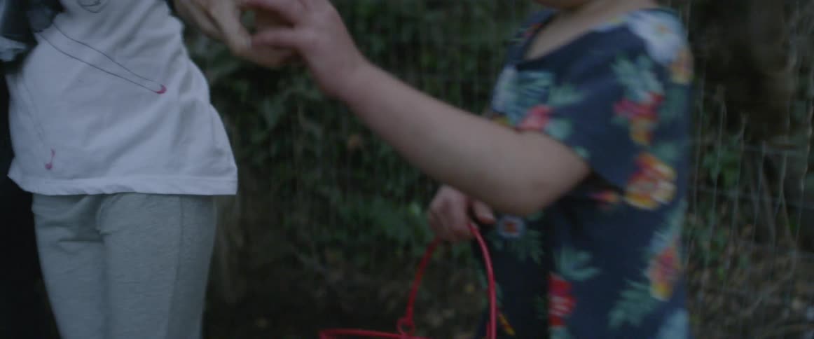 Girl hands an egg to a smaller girl who puts it in a wire basket