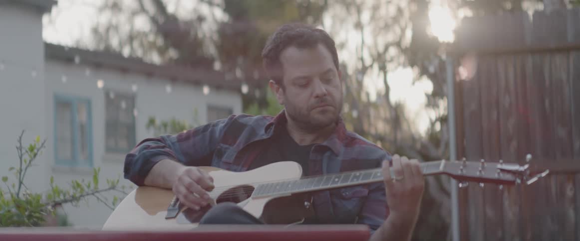 A man plays guitar on a back patio