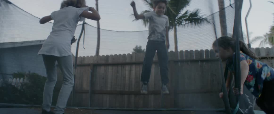 Three children jump on a trampoline