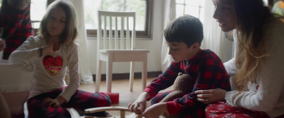 A mother hugs her son as the family plays on their living room floor in daylight