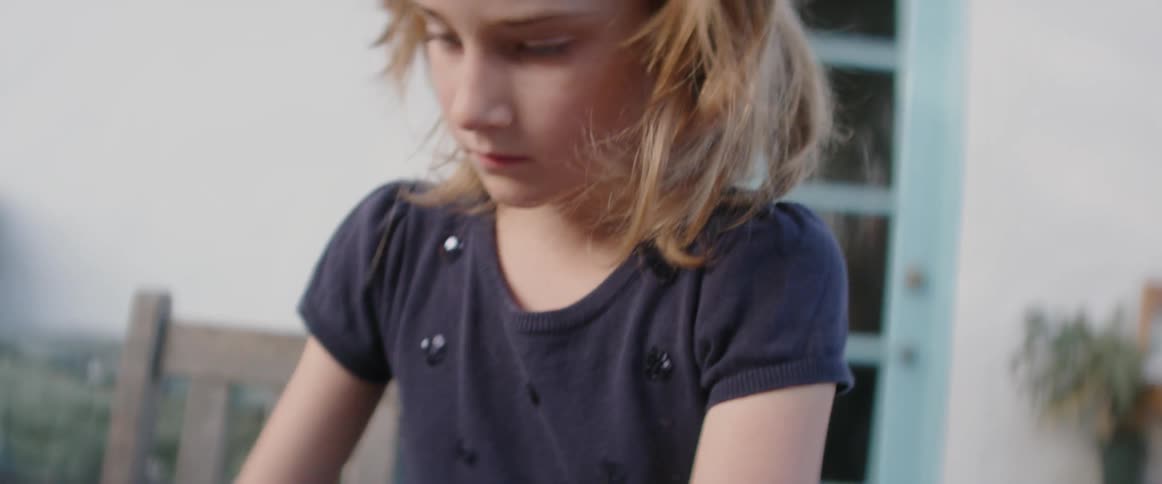 A girl plays with rocks on a patio table
