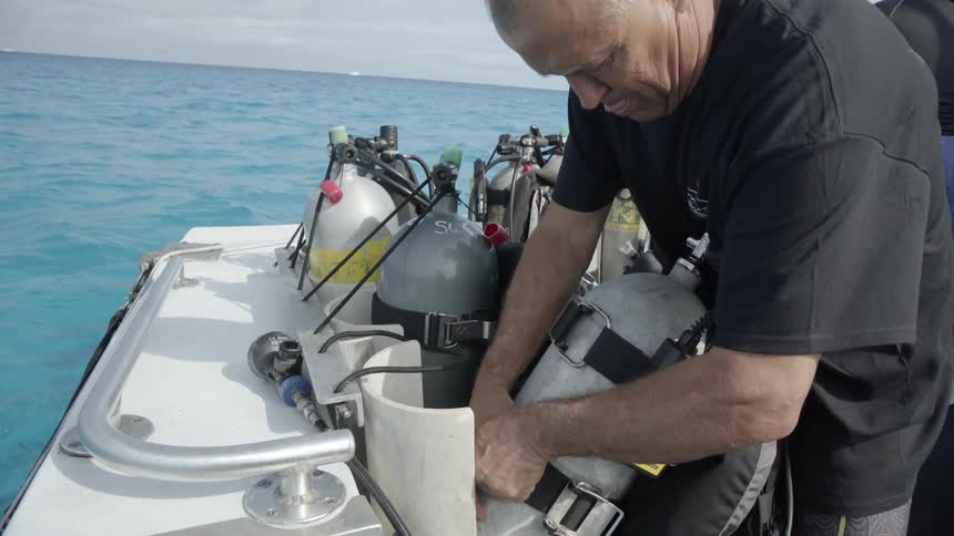 A man inspects an oxygen tank on a boat on the ocean