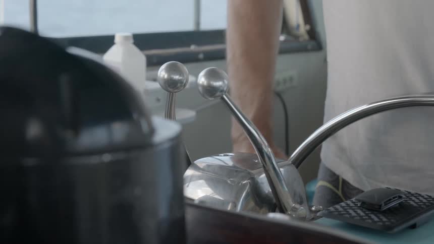 A man steers a boat wheel