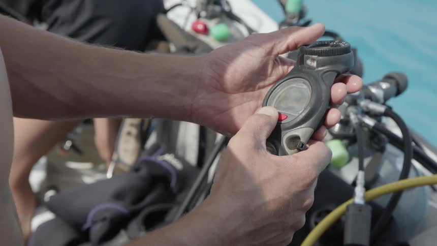 A man is checking a diving regulator while standing on a boat in daylight