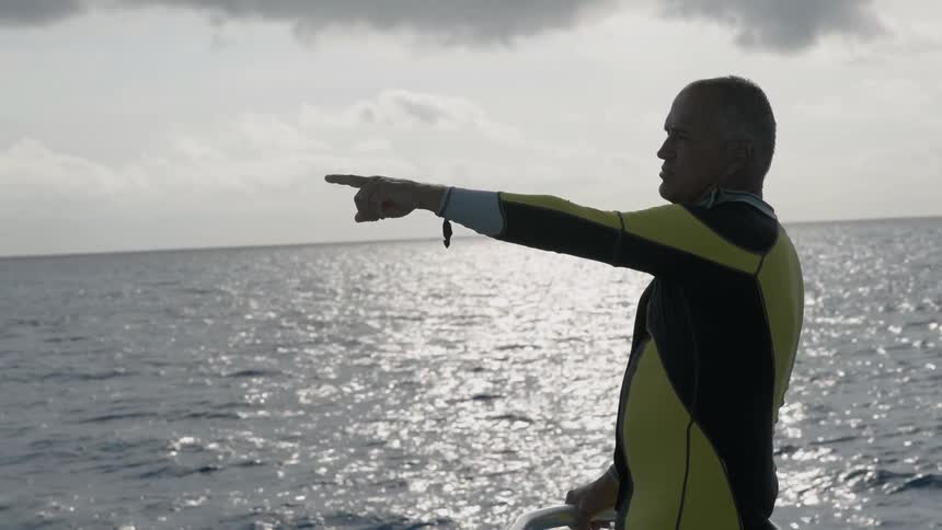 Man riding on a boat points out on a sunny day