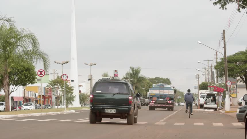 A man rides a bicycle on a city street as vehicles drive by