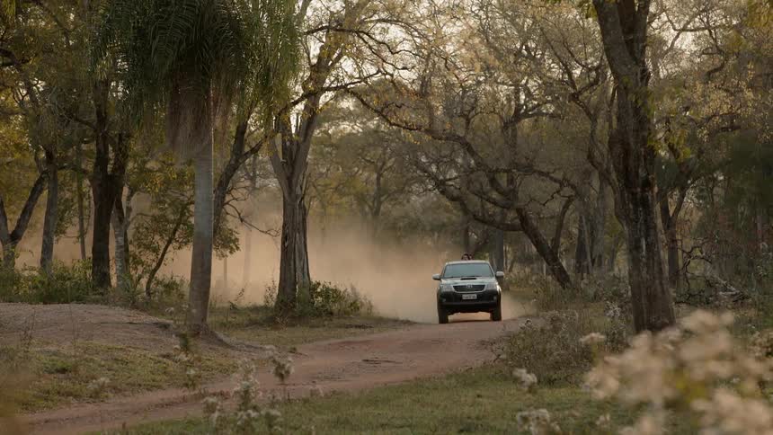 A vehicle drives down a dirt road