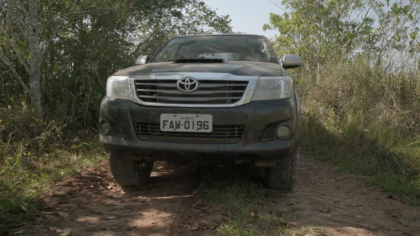 Vehicle drives down a narrow tree lined dirt path