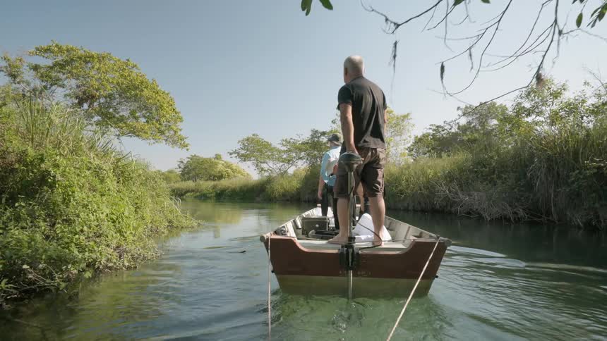 The man is steering the small boat with people in it