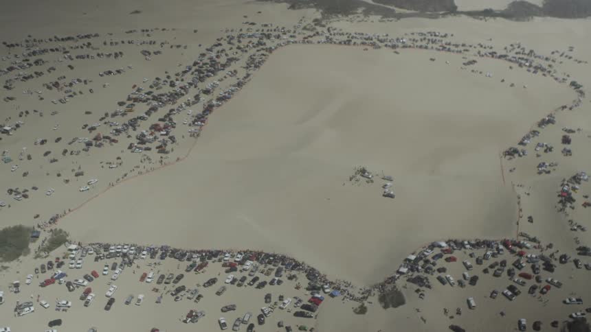 Overhead view of many vehicles parked on the sand