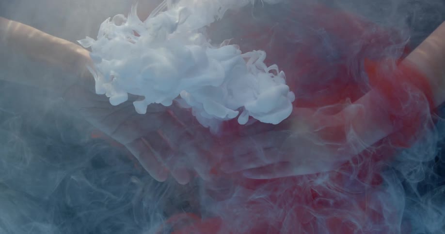 Hands submerged in water unclasp as white dye floats around them