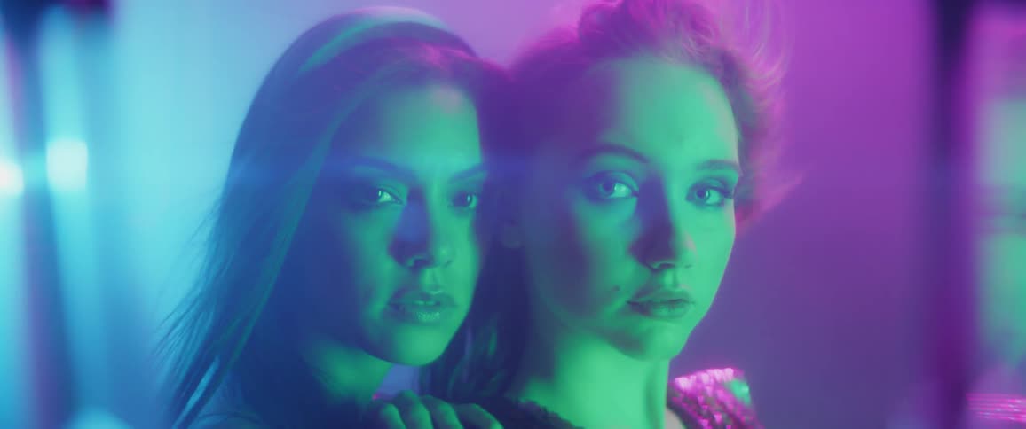 Two women stand together under different colored lights