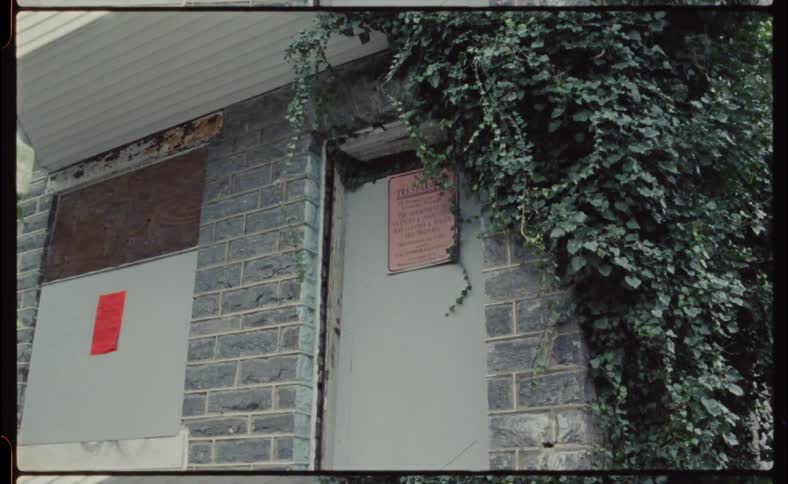 Legal notices are posted on boarded up window and closed door
