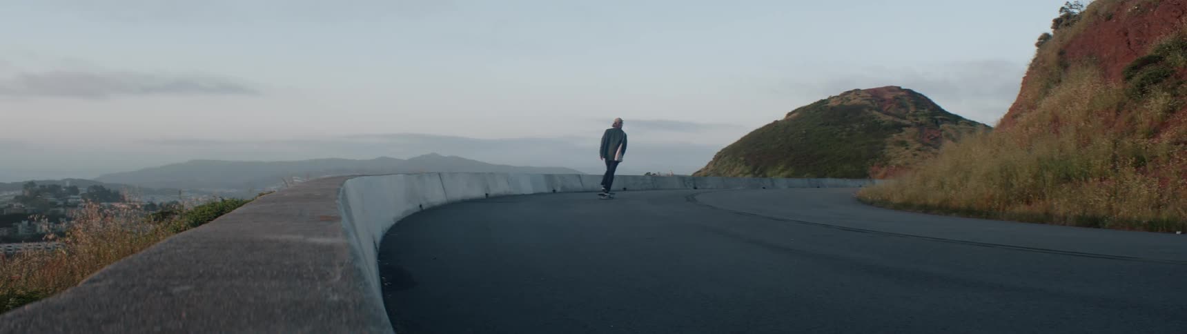 A person rides their skateboard around the curved road