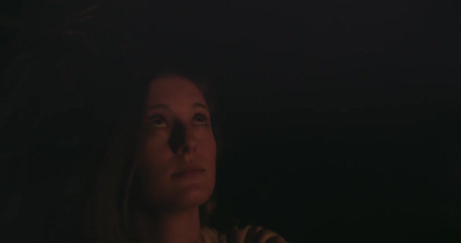 Woman sitting in the dark looks towards the sky