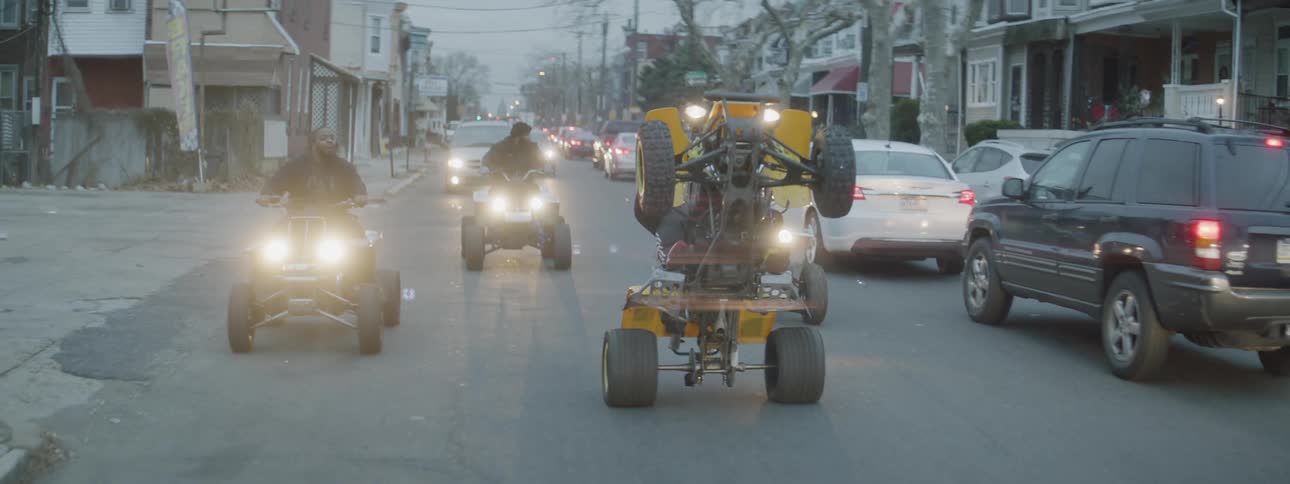 A four wheeler does a wheelie on the street