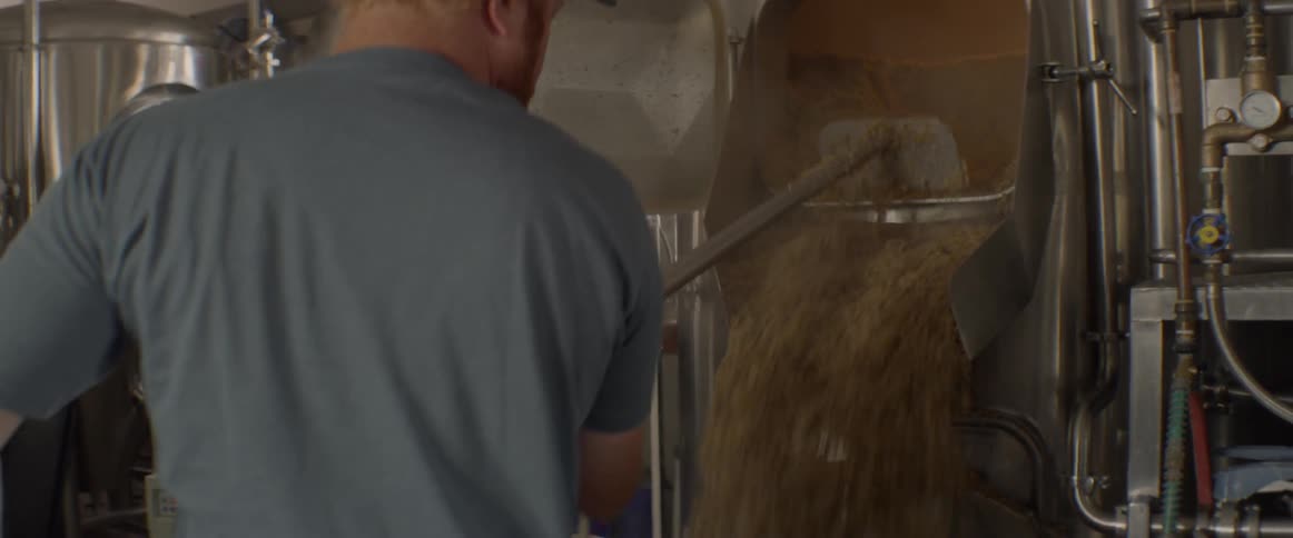 A man scoops grains from machinery