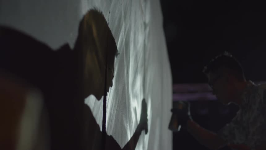 Man spray paints on a plastic surface